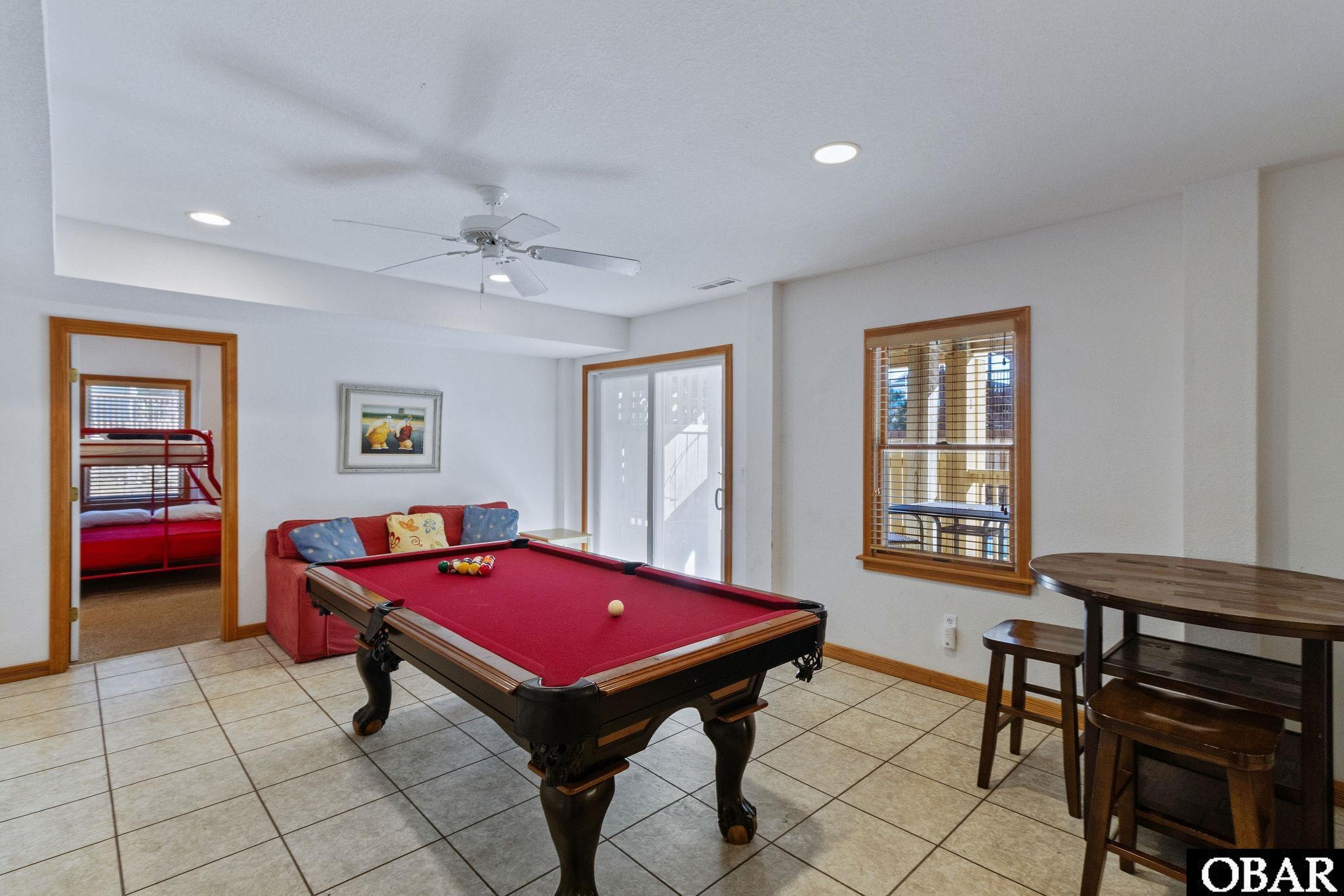 Game room with a red-felt pool table, red sofa, and doorway to a bedroom with a red bunk bed.