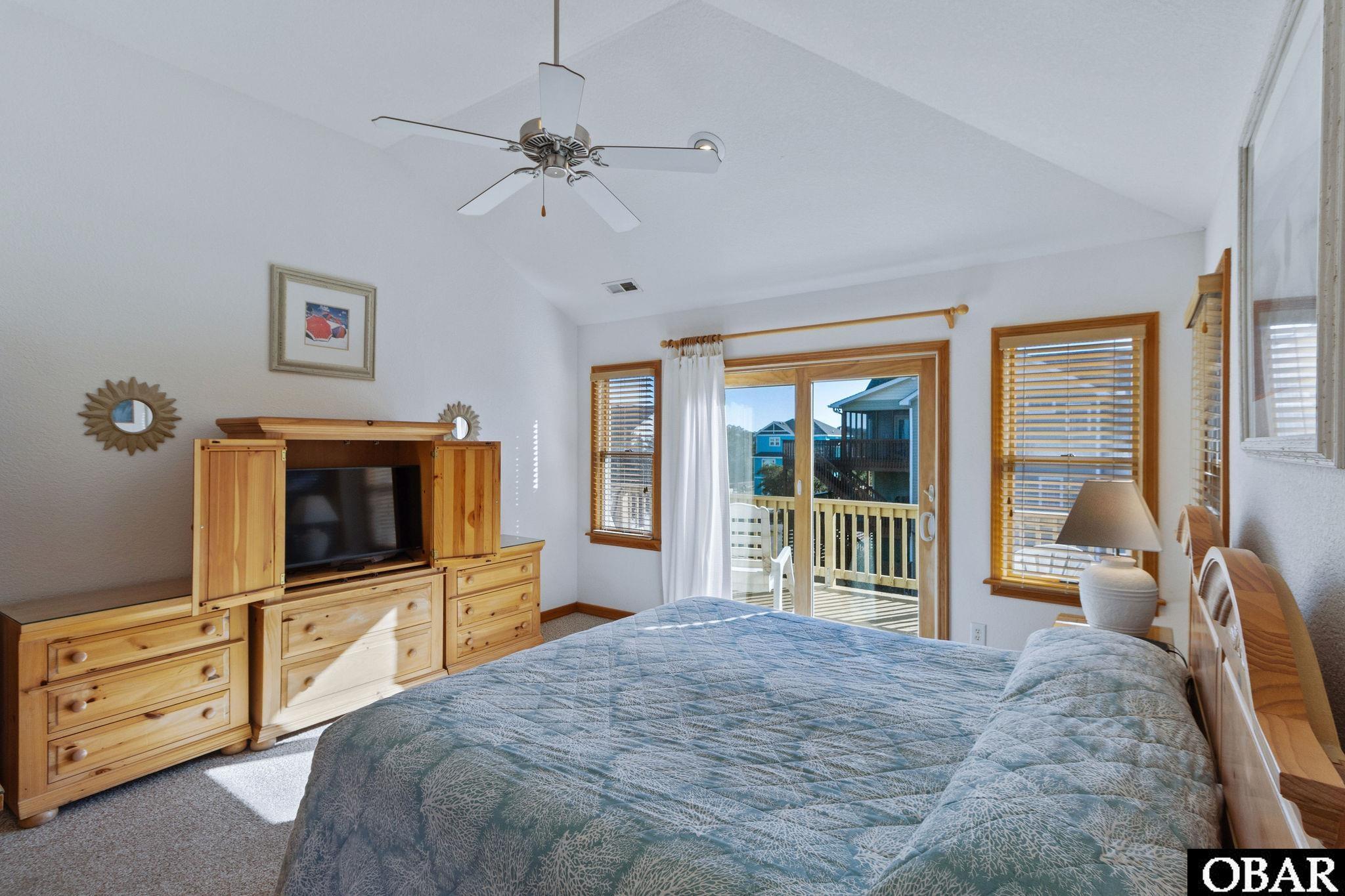Bedroom with a blue patterned bedspread, pine furniture, and sliding doors to a balcony.