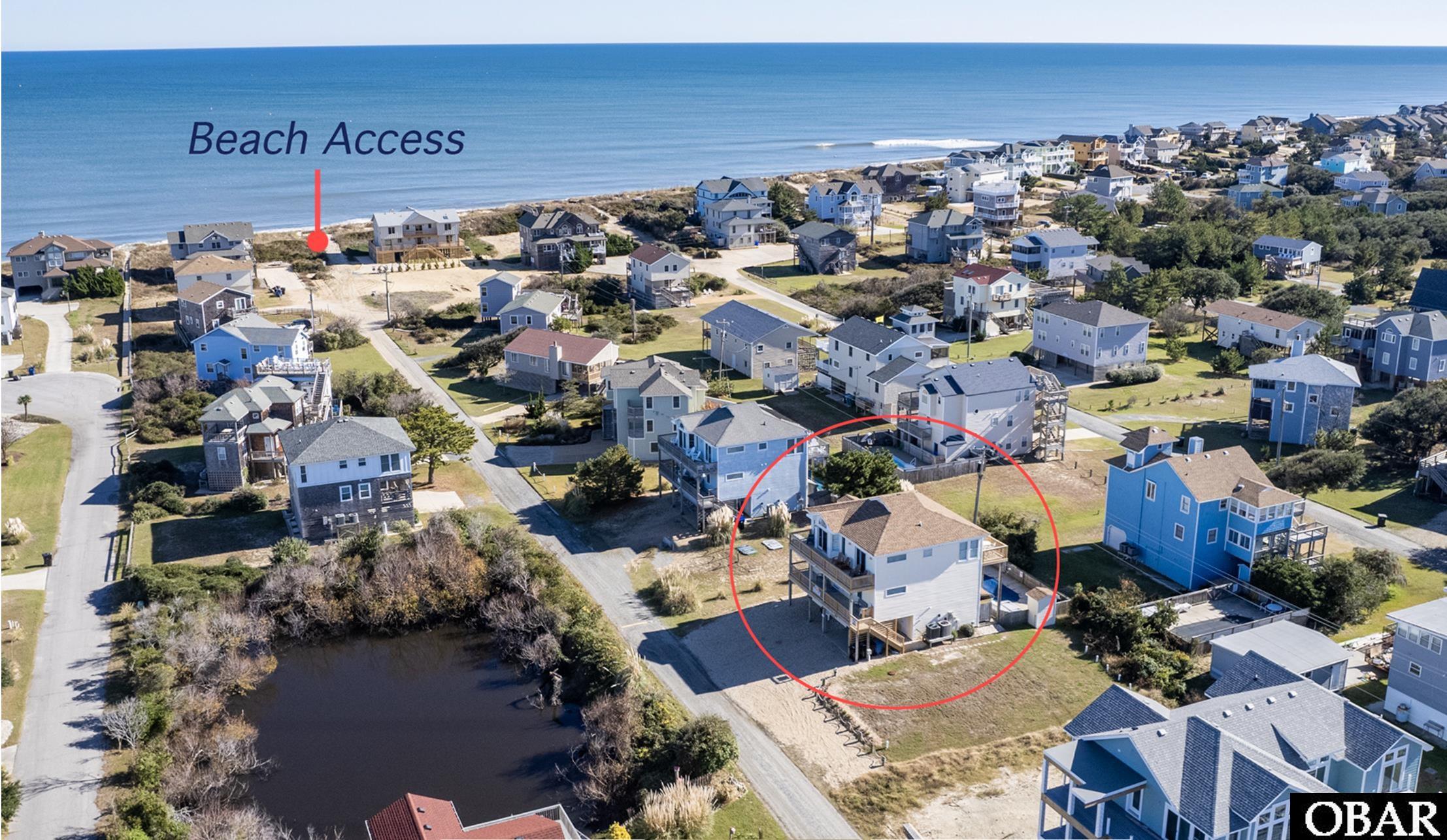 Aerial view of a coastal neighborhood, with the property circled near beach access.
