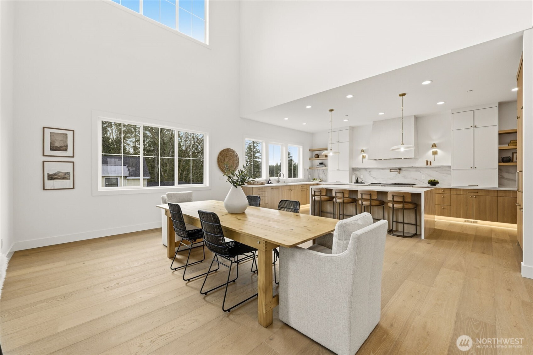 Open dining room and kitchen with vaulted ceilings, tall windows, and a large island.