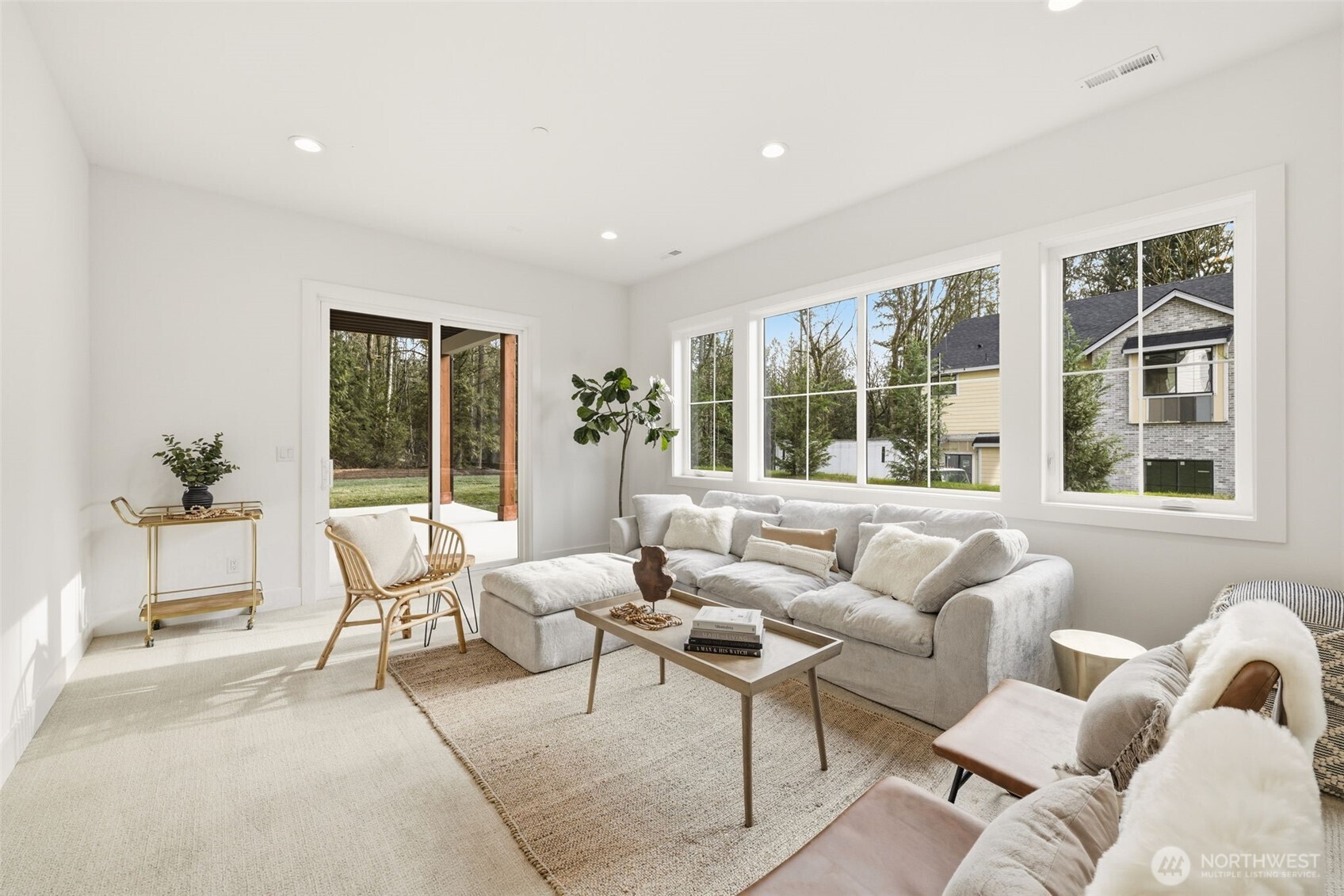 Furnished living room with a light sectional, large windows, and sliding doors to a patio.