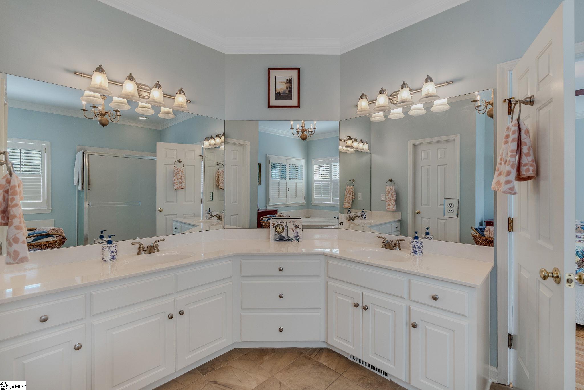 Bathroom with a wraparound double vanity, broad mirrors, and pale blue walls.