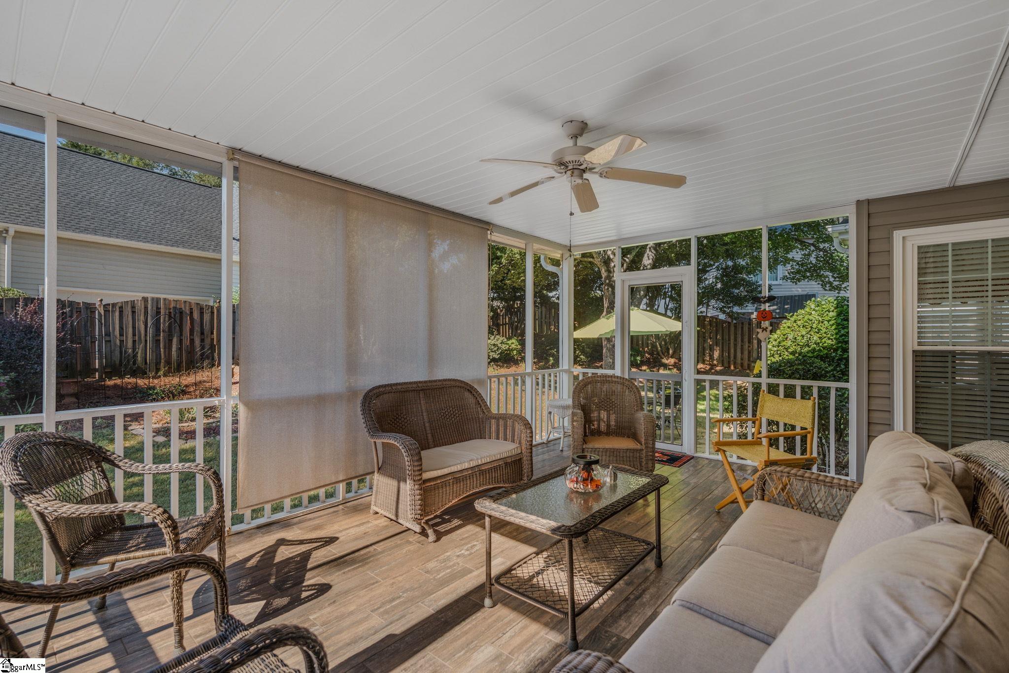 Screened porch furnished with wicker seating and a sofa, opening onto a fenced backyard.
