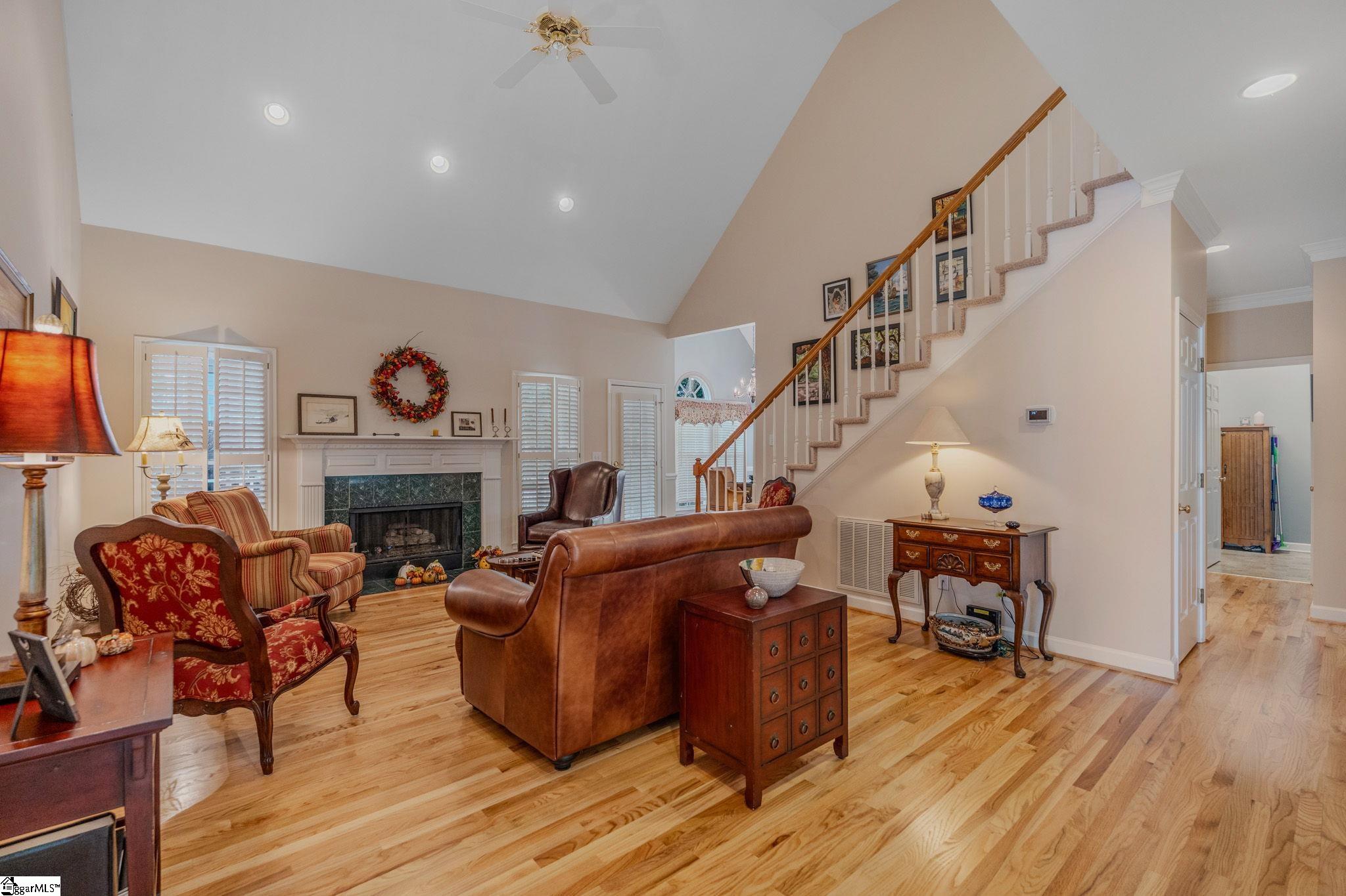 Living room with a fireplace, hardwood floors, and a staircase.