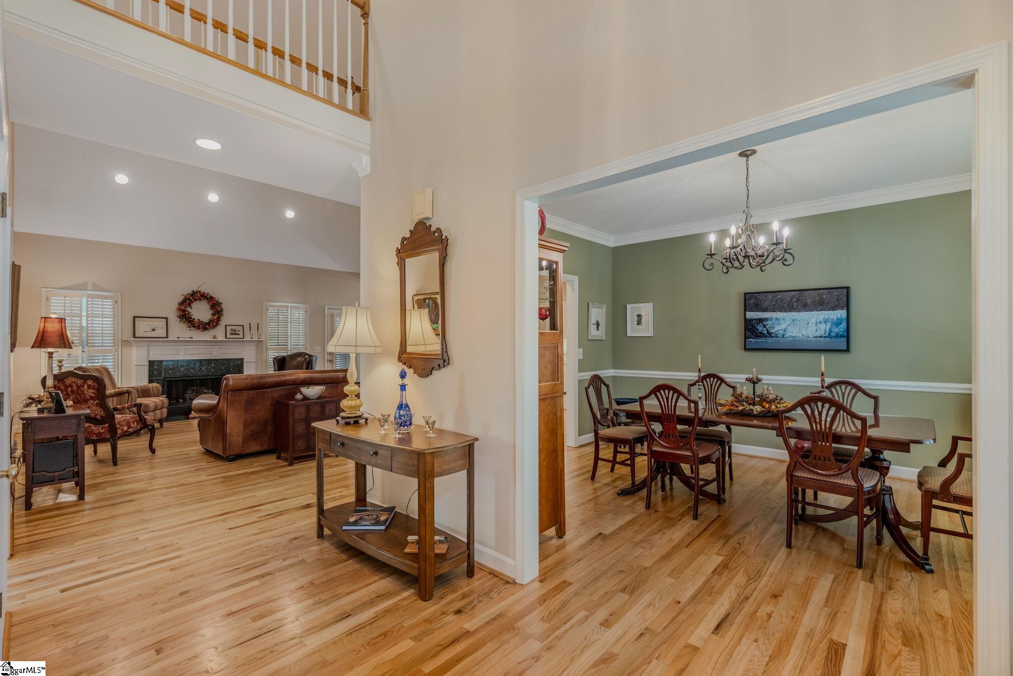 Living and dining rooms with hardwood floors, a fireplace, and a chandelier.