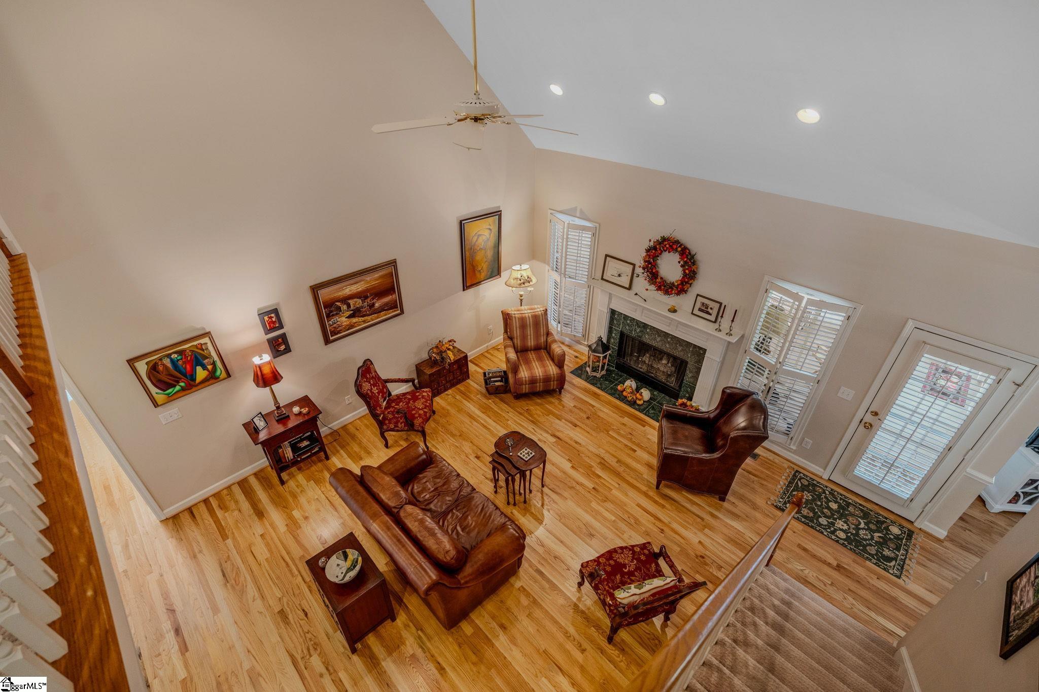 Furnished living room with vaulted ceiling, hardwood floors, fireplace, and leather seating.