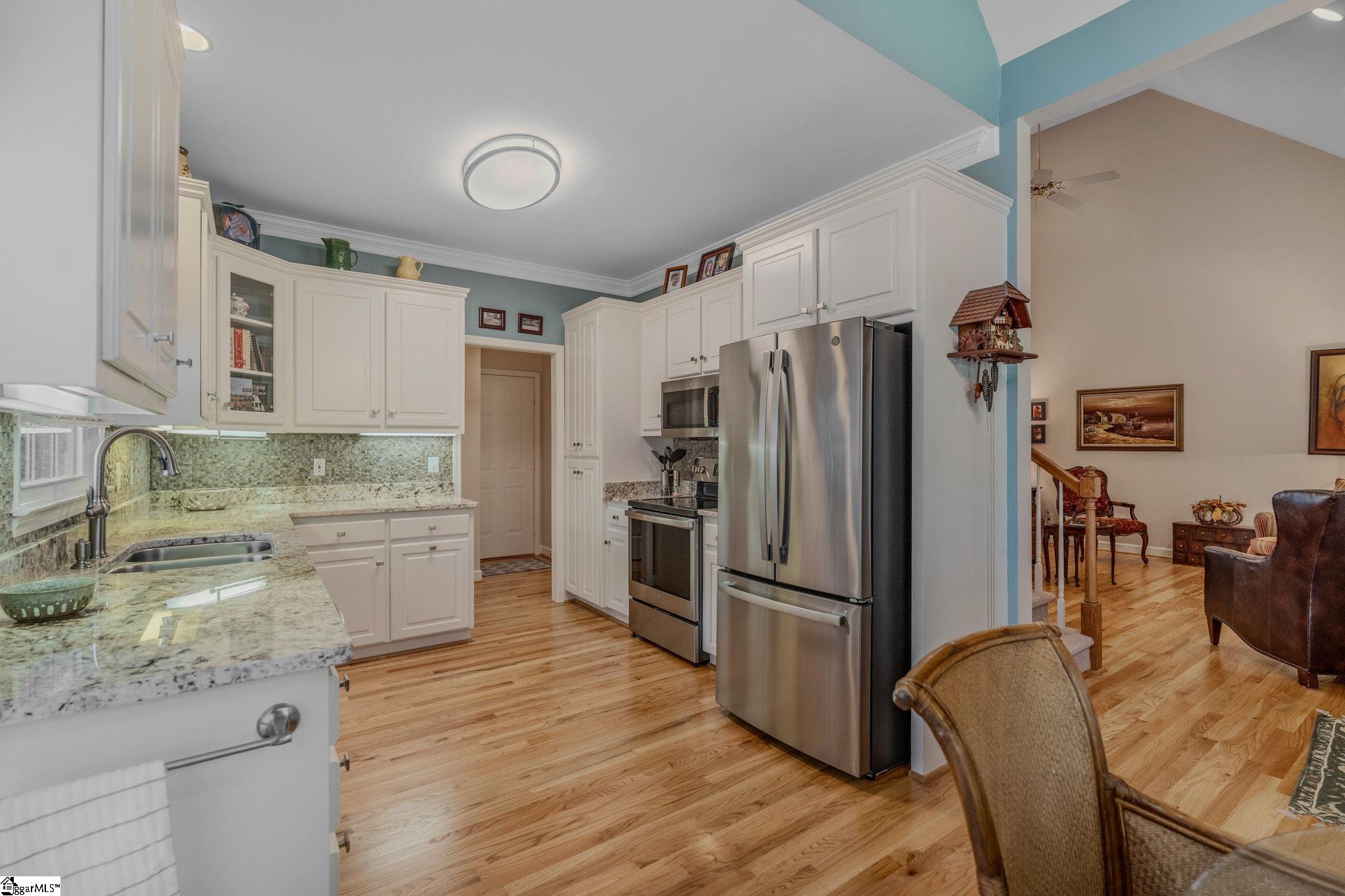 Kitchen with white cabinets, granite counters, stainless steel appliances, and hardwood floors.