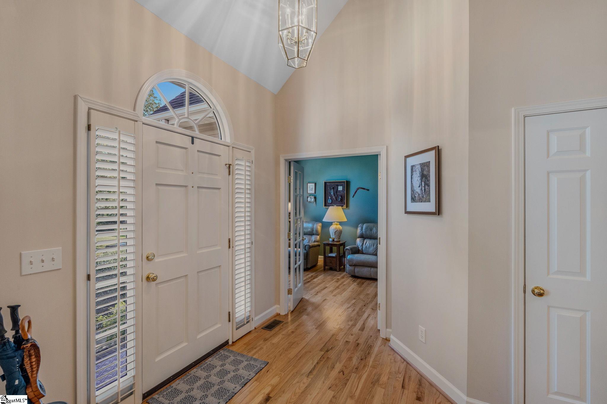 Entry foyer with an arched window over the front door and a view into a furnished sitting room.