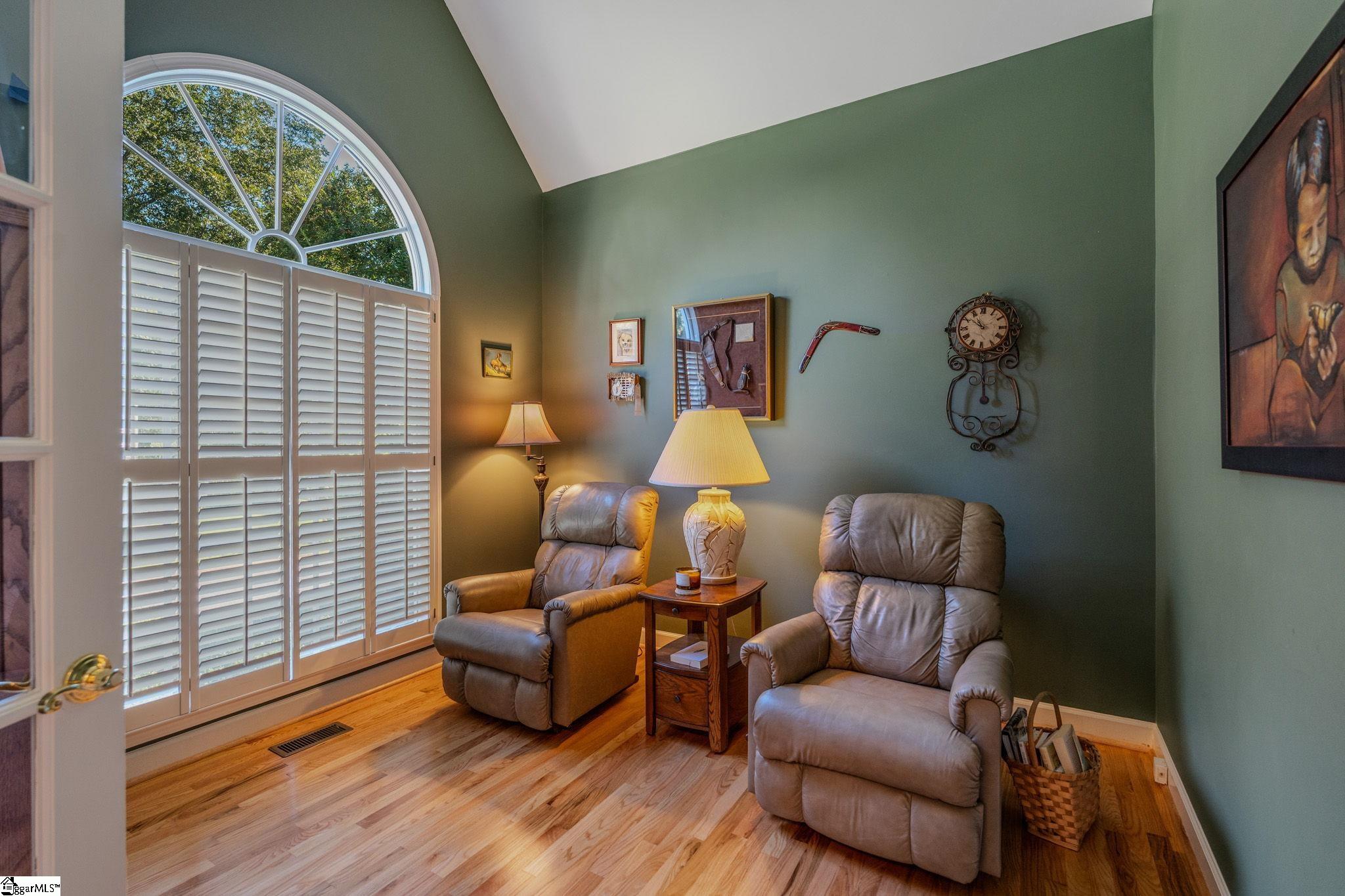 Furnished sitting room with leather recliners and a large arched window with plantation shutters.