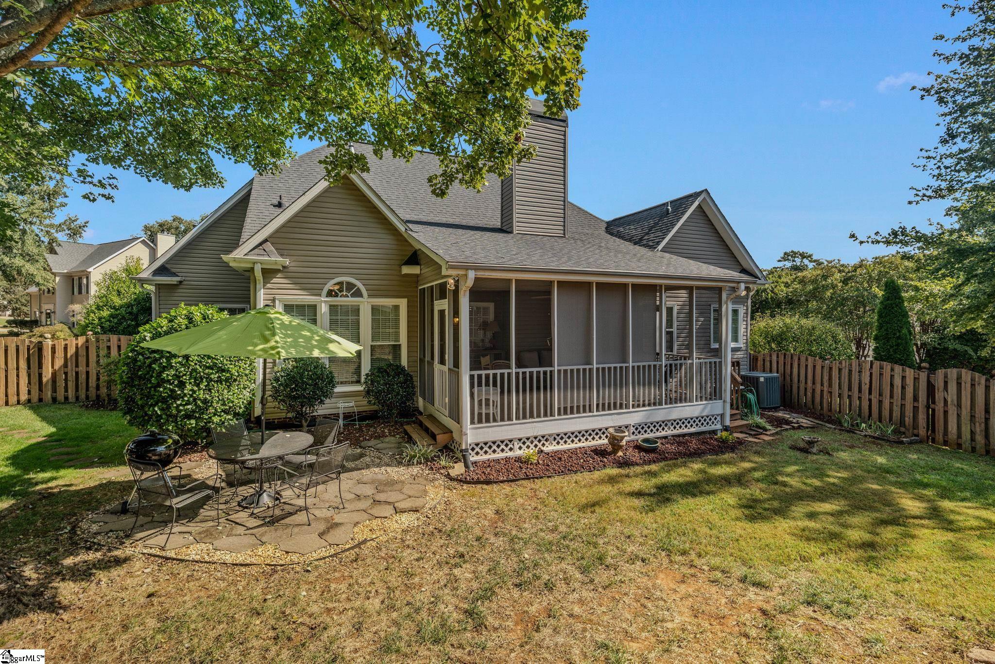 House rear with a screened porch and fenced yard; a green umbrella shades the patio dining set.