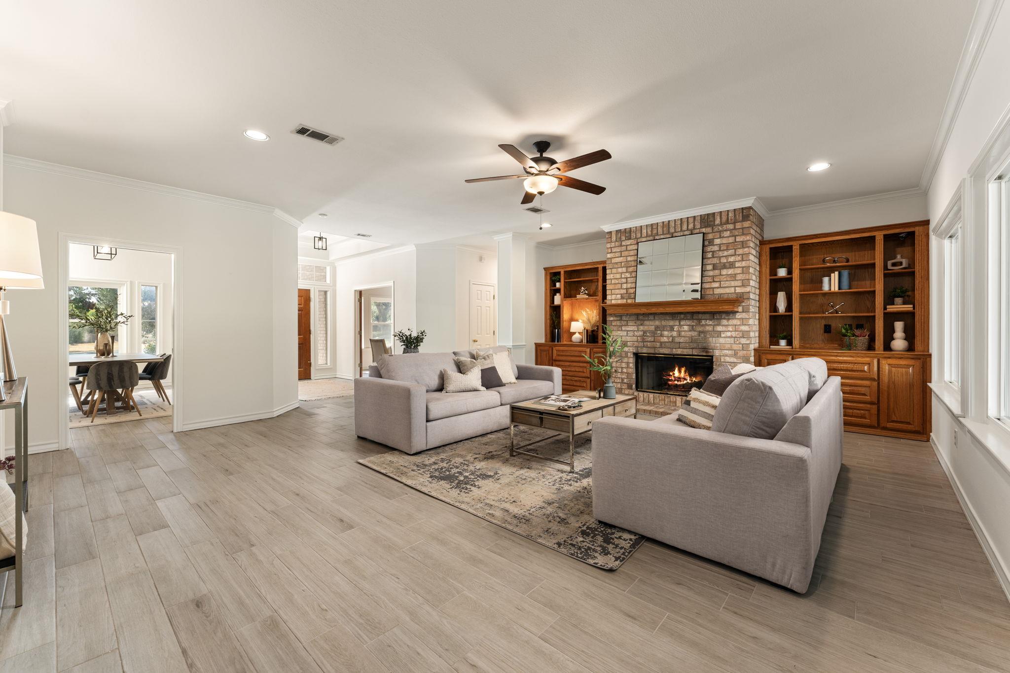 Living room with a brick fireplace, built-in wooden shelving, and two sofas.