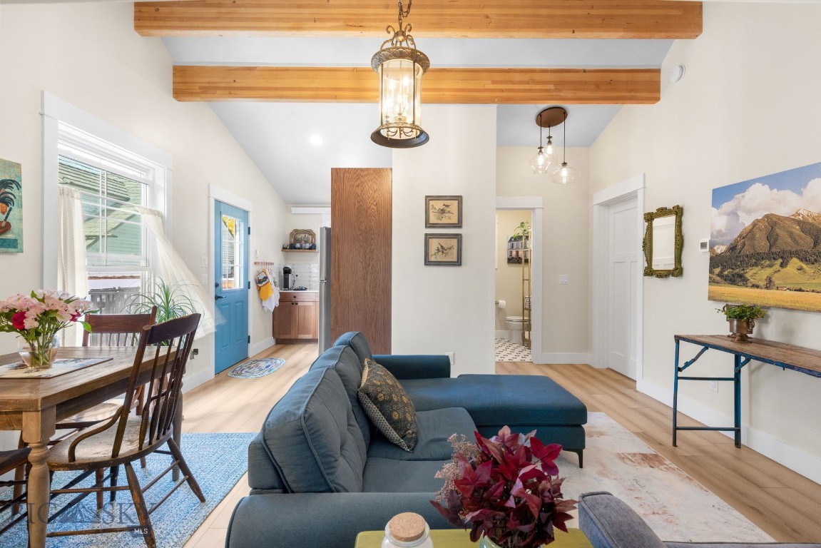 Open-plan living room with blue sectional, dining table, and exposed timber ceiling beams.