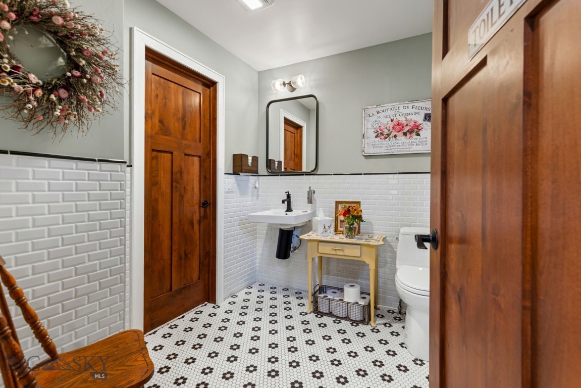 Bathroom with patterned floor tile, white subway tile, and a wooden console table beside the sink.