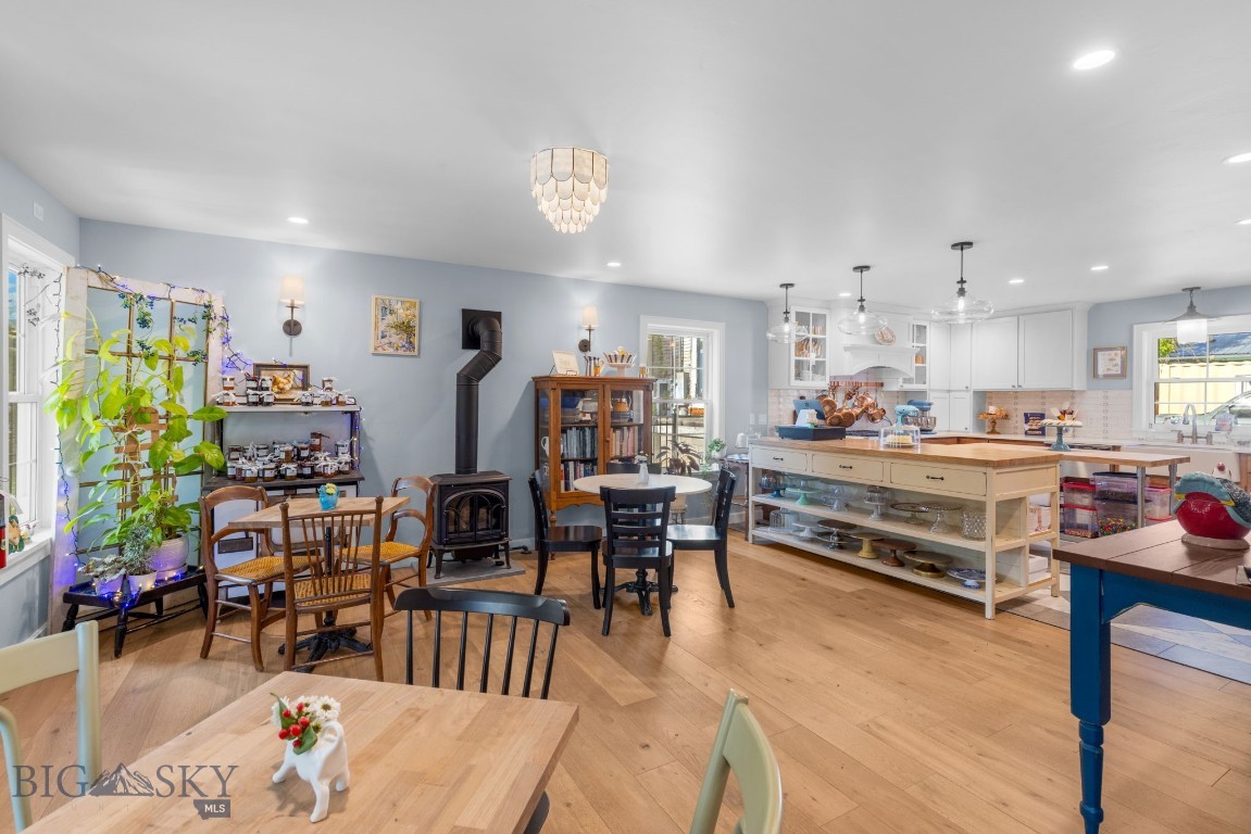 Kitchen and dining area with a large wood-topped island, white cabinets, and a black wood stove.