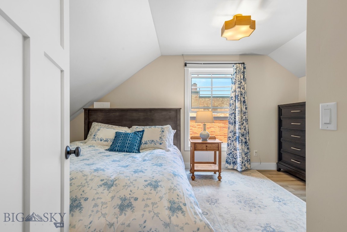 Bedroom with blue floral bedding, a sloped ceiling, and a curtained window.