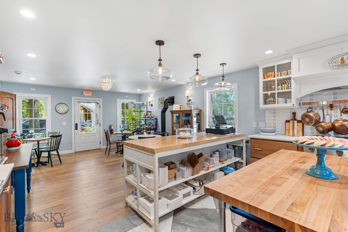 Bright kitchen with a large butcher-block island, open shelving, and pendant lights.