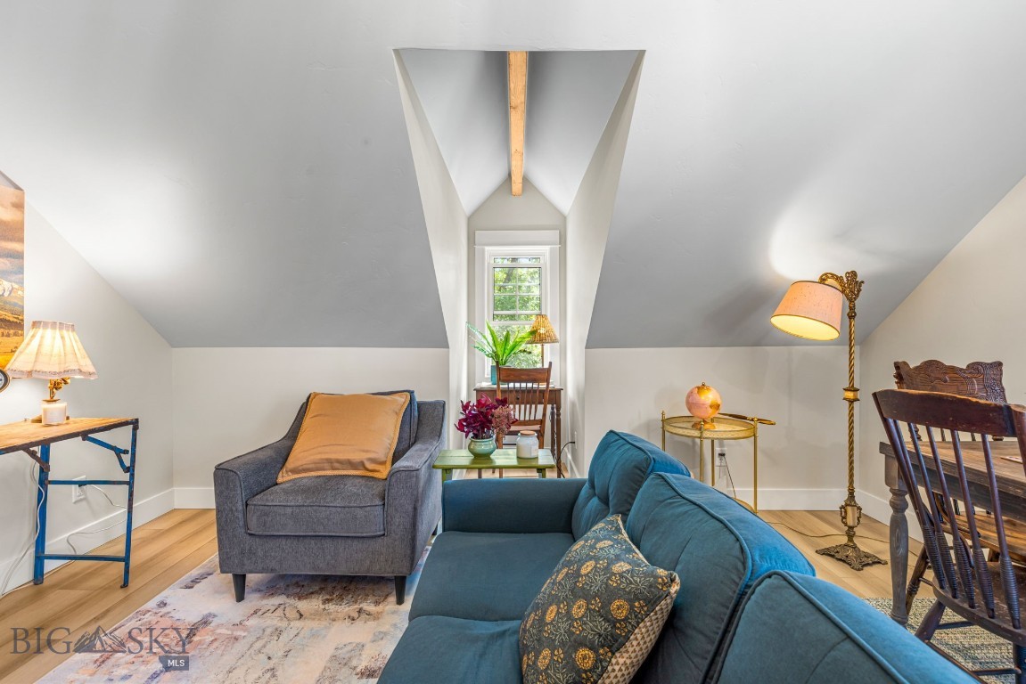 Furnished attic living room with sloped ceilings, exposed beam, and dormer window.