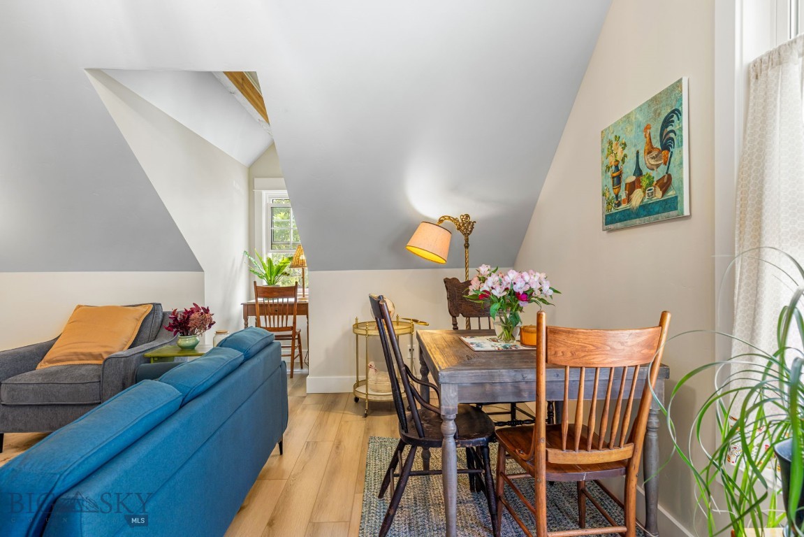 Furnished living and dining area with blue sofas, a wooden table, and a sloped ceiling.