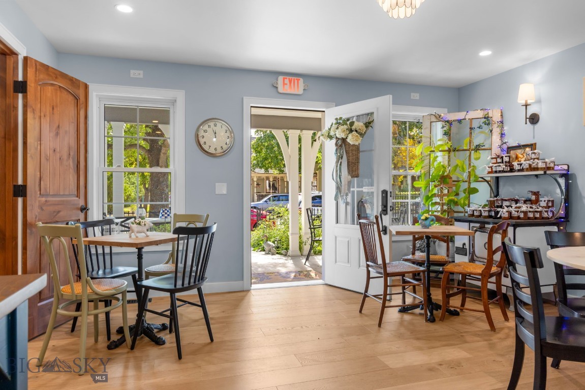 Furnished café interior with wooden tables, product shelves, and an open door to the patio.