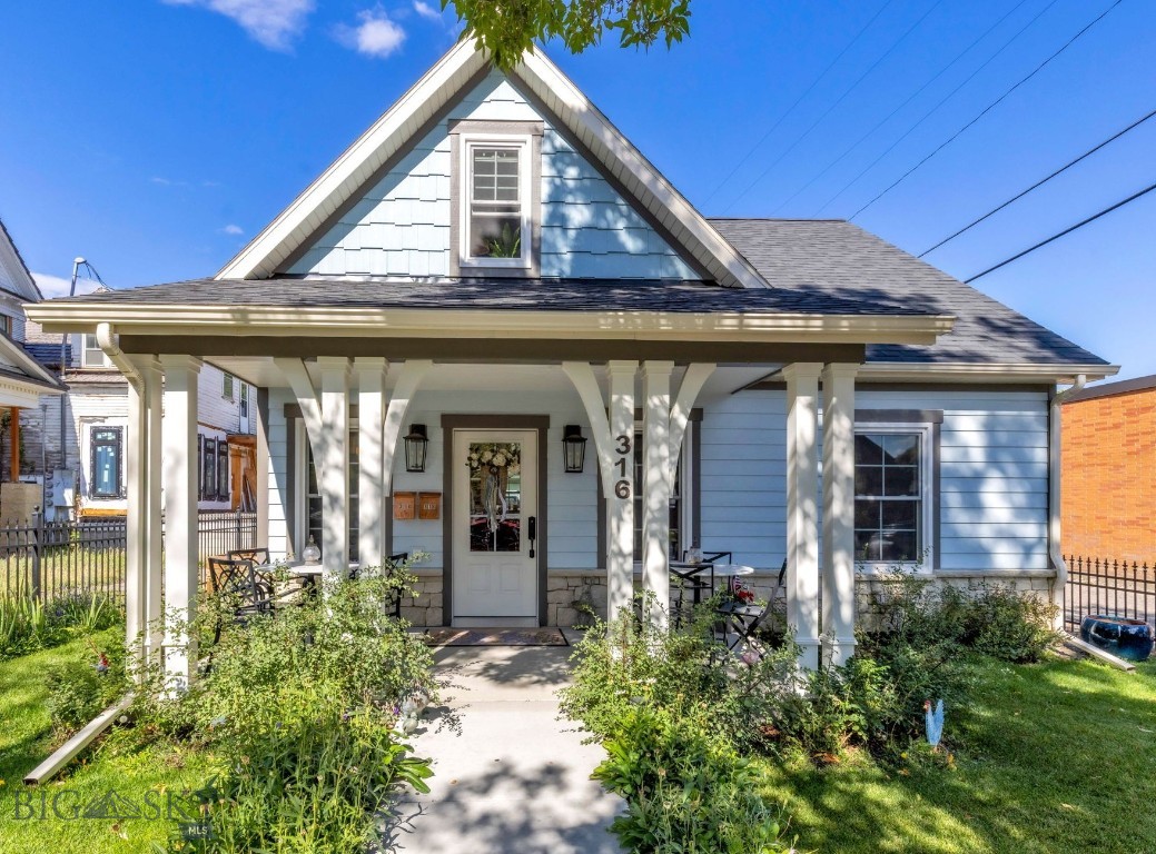 Light blue gable-front house with a covered porch and garden-lined walkway.