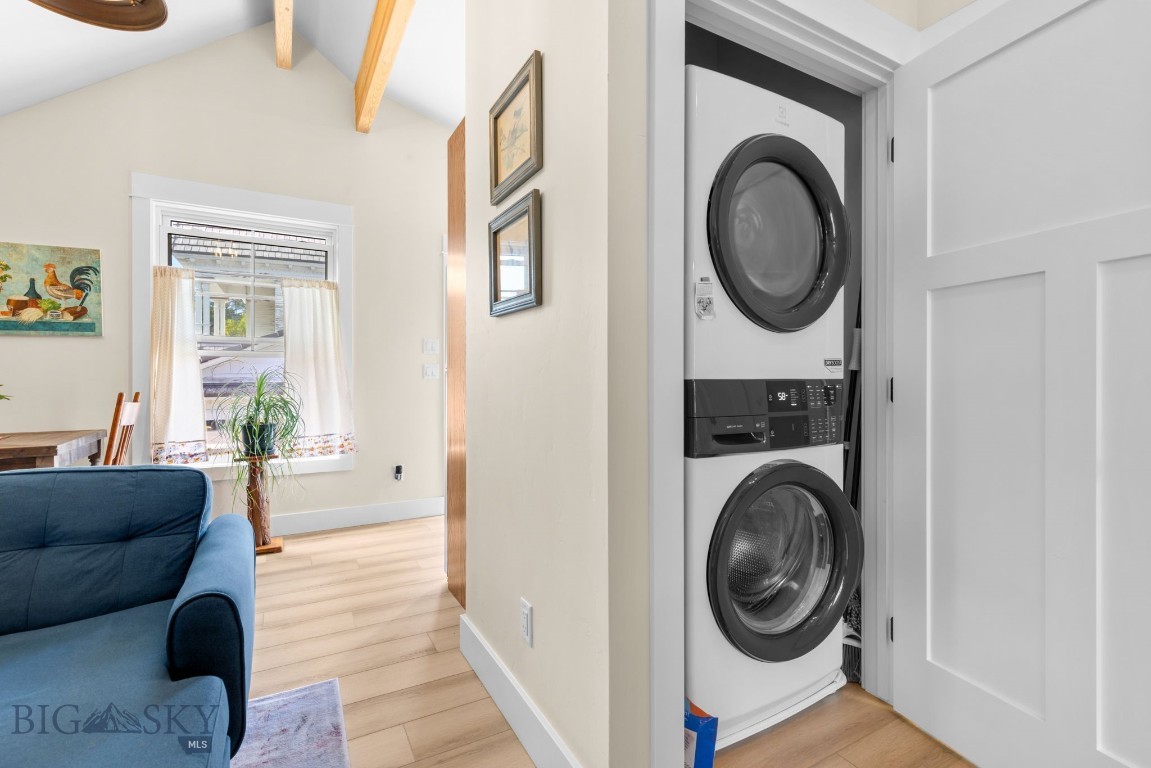 Stacked washer and dryer in a closet beside a bright living and dining area.