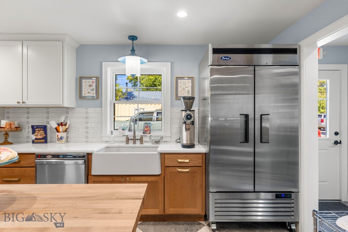 Kitchen with a large stainless-steel refrigerator, farmhouse sink, and butcher-block island.