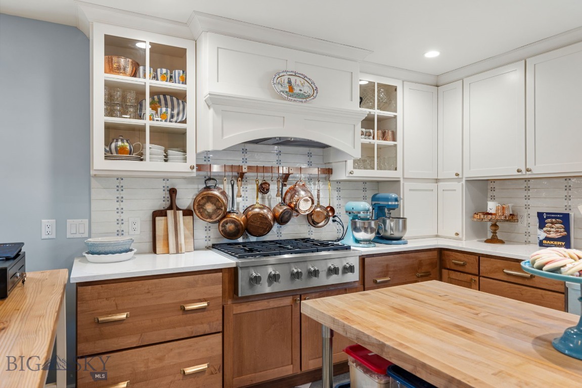 Kitchen with a large butcher-block island, copper pots, and a wide stainless-steel range.