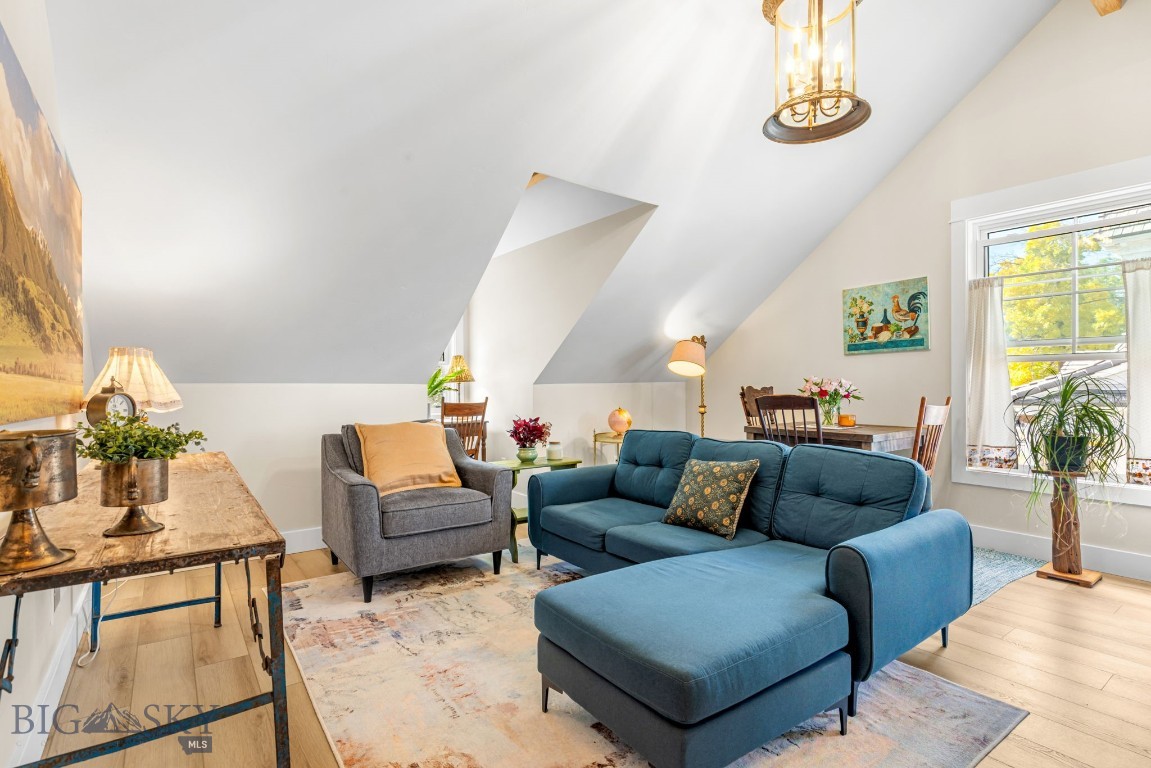 Living room with a blue sectional and chaise beneath a sloped ceiling, furnished with a dining area.