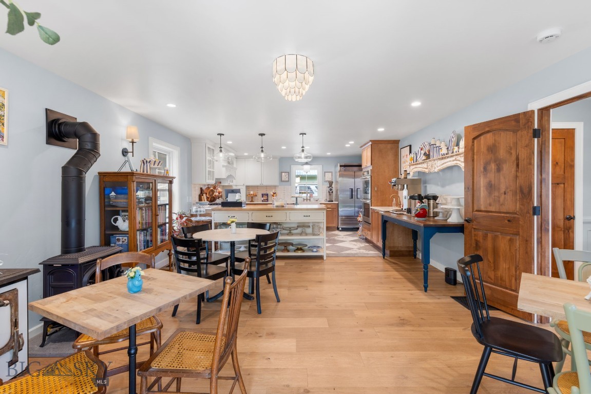 Open kitchen and dining area with a central island, wood floors, and a black wood stove.