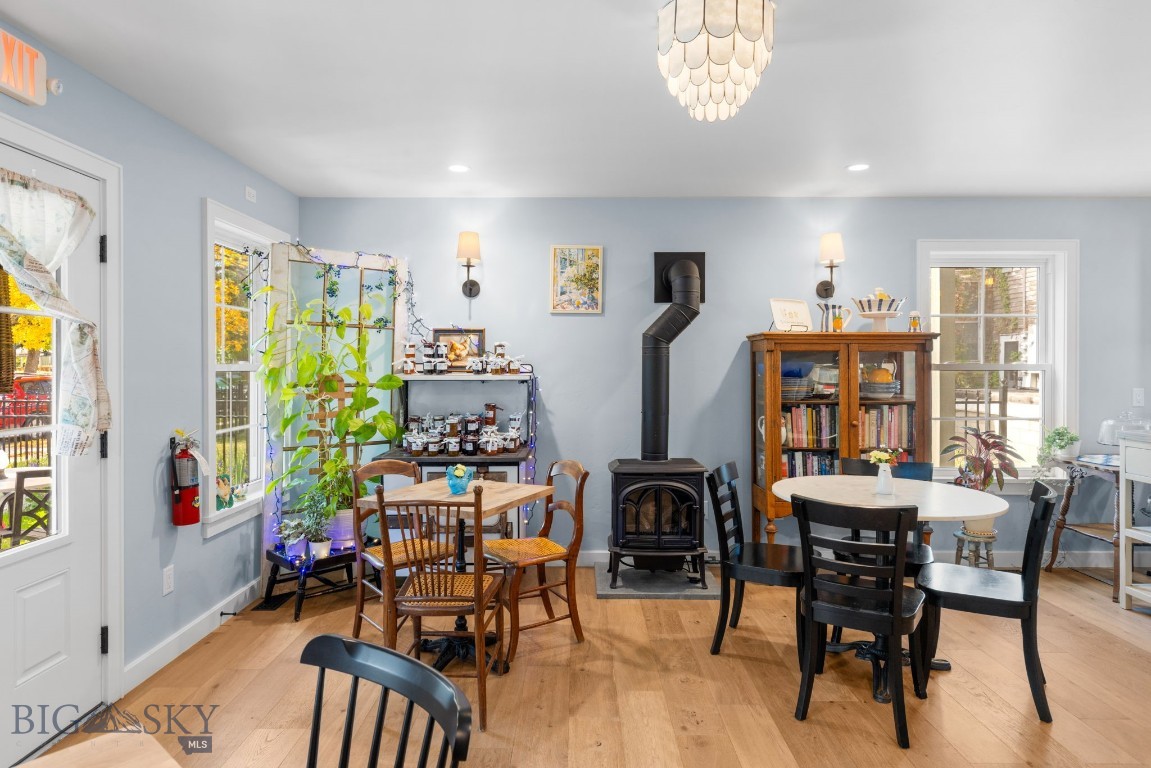 Dining area with a black wood stove, two tables, and a wooden bookcase.