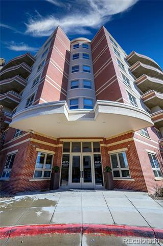 Brick condominium entrance with curved balconies and snow patches along the walkway.