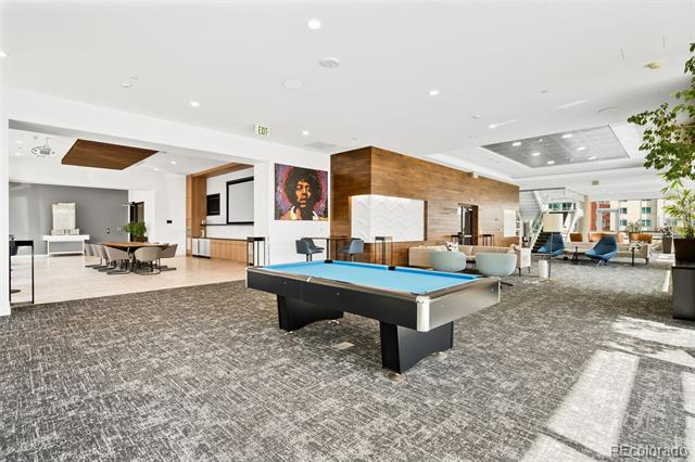 Condominium lounge with a blue-felt pool table, wood-paneled feature wall, and seating areas.