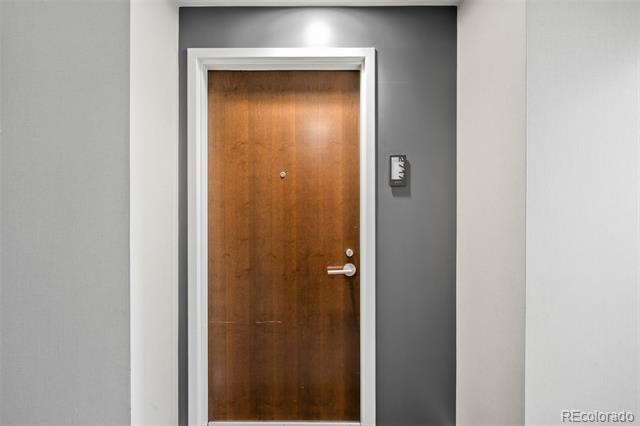 Apartment entry door with a wood finish, silver handle, and white trim.