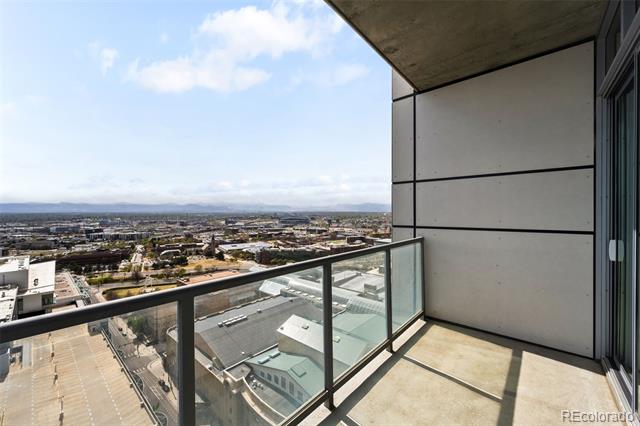 Condo balcony with glass railing overlooking downtown Denver and the surrounding cityscape.