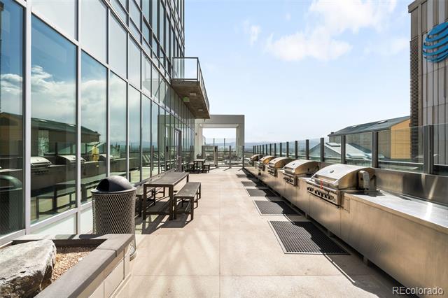 Rooftop terrace with stainless-steel grills, outdoor seating, and city views.
