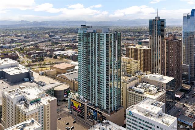 Aerial view of downtown Denver towers with the Rocky Mountains in the distance.