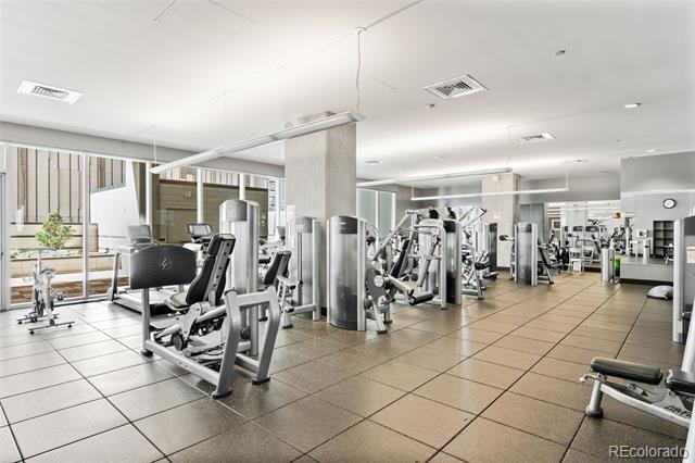 Condominium fitness room with rows of exercise machines and large windows.