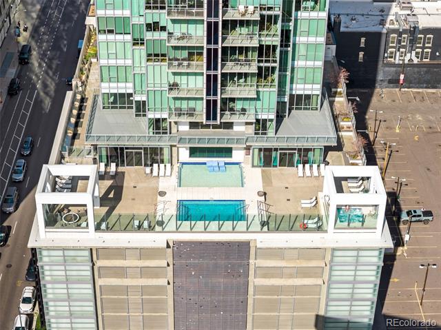 Modern glass high-rise with a rooftop pool and terrace.