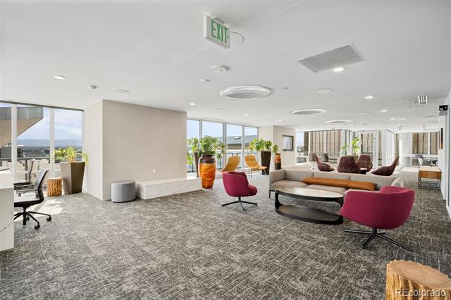 Furnished communal lounge with magenta chairs, a long sofa, and large windows.