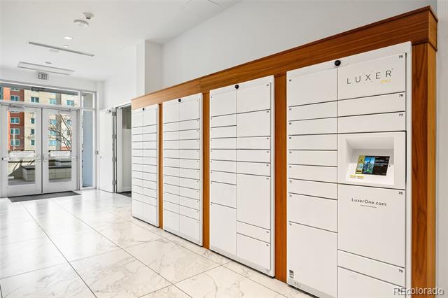 Condominium lobby with white parcel lockers, wood paneling, and marble-look tile flooring.