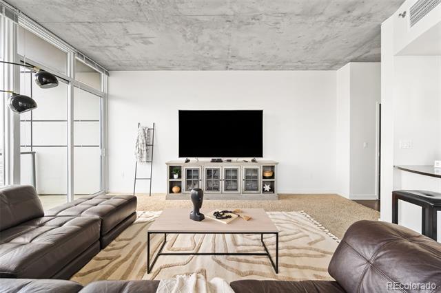 Furnished living room with leather sofas, glass doors, and a distinctive exposed concrete ceiling.