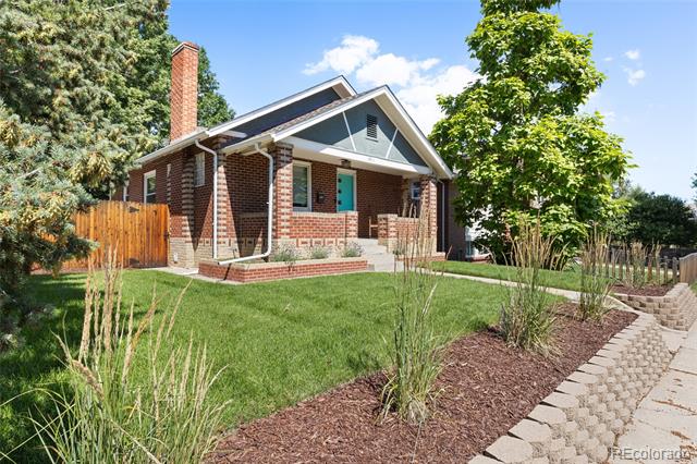 Brick house with a covered front porch, green lawn, and landscaped stone path.