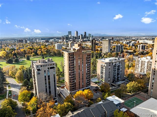 Aerial view of Denver apartment buildings and skyline amid autumn trees.