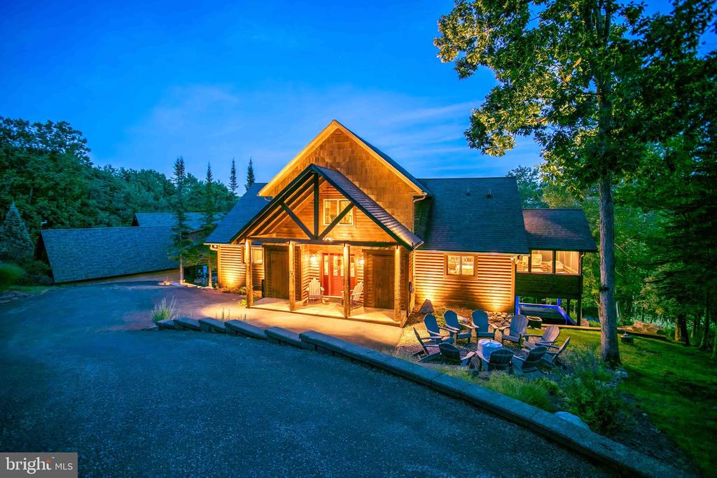 Wood-sided cabin glowing at dusk, with a covered entry and outdoor seating.