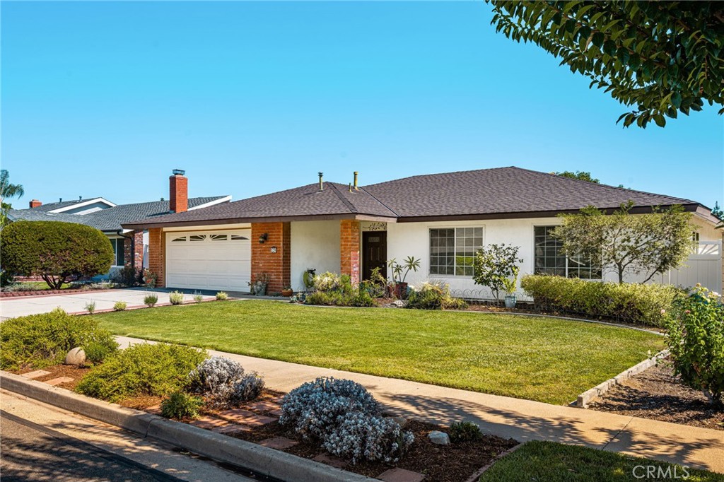 Single-story home with brick accents, an attached garage, and a neatly landscaped front lawn.