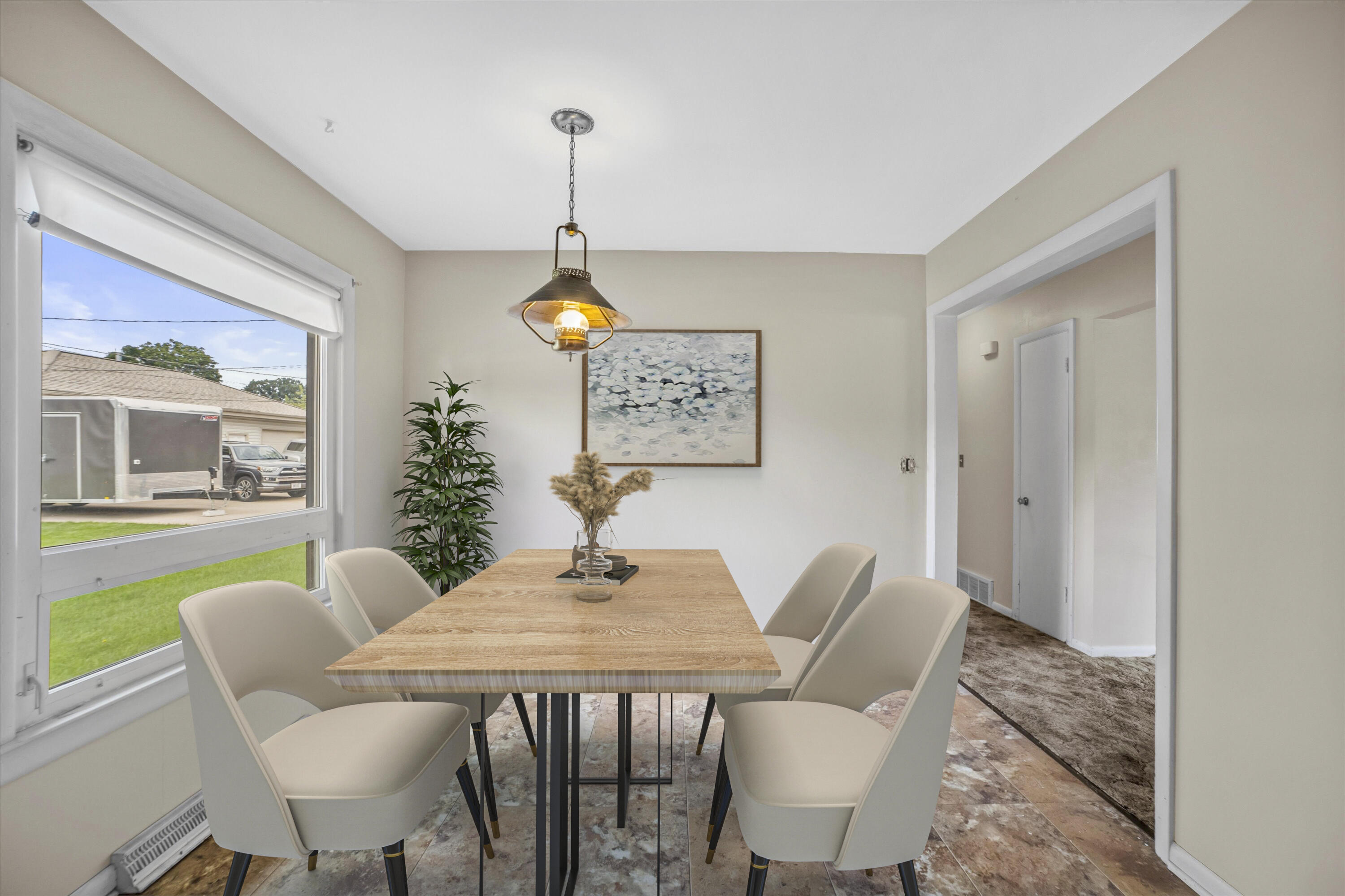 Dining room with a wood table and four chairs beside a large front-facing window.
