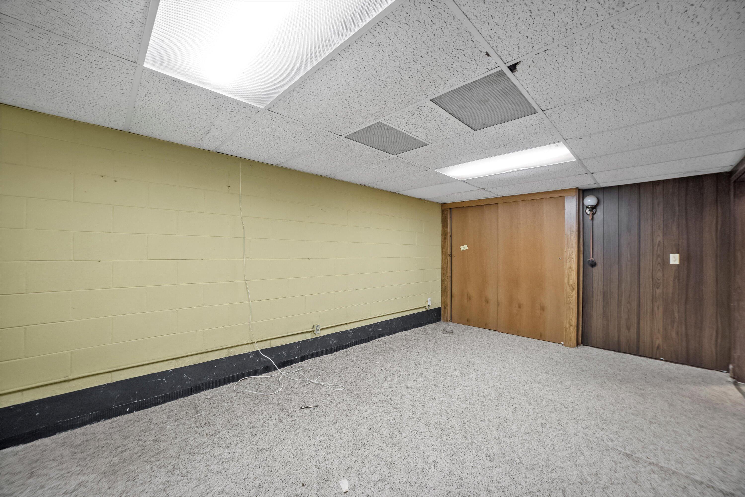 Vacant carpeted room with yellow block wall, wood paneling, and a large sliding wooden door.