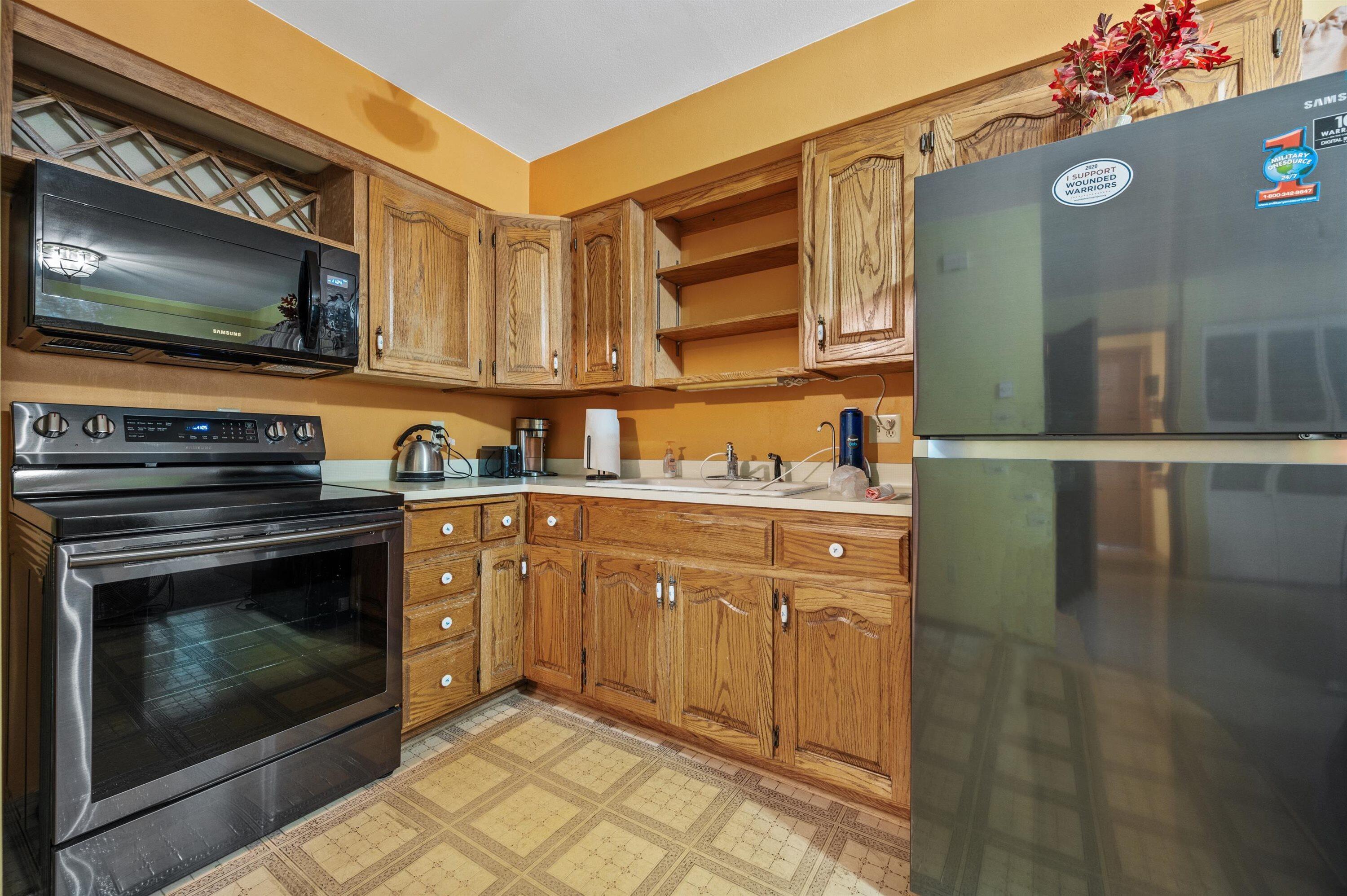 Kitchen with oak cabinets, stainless steel appliances, and patterned tile flooring.