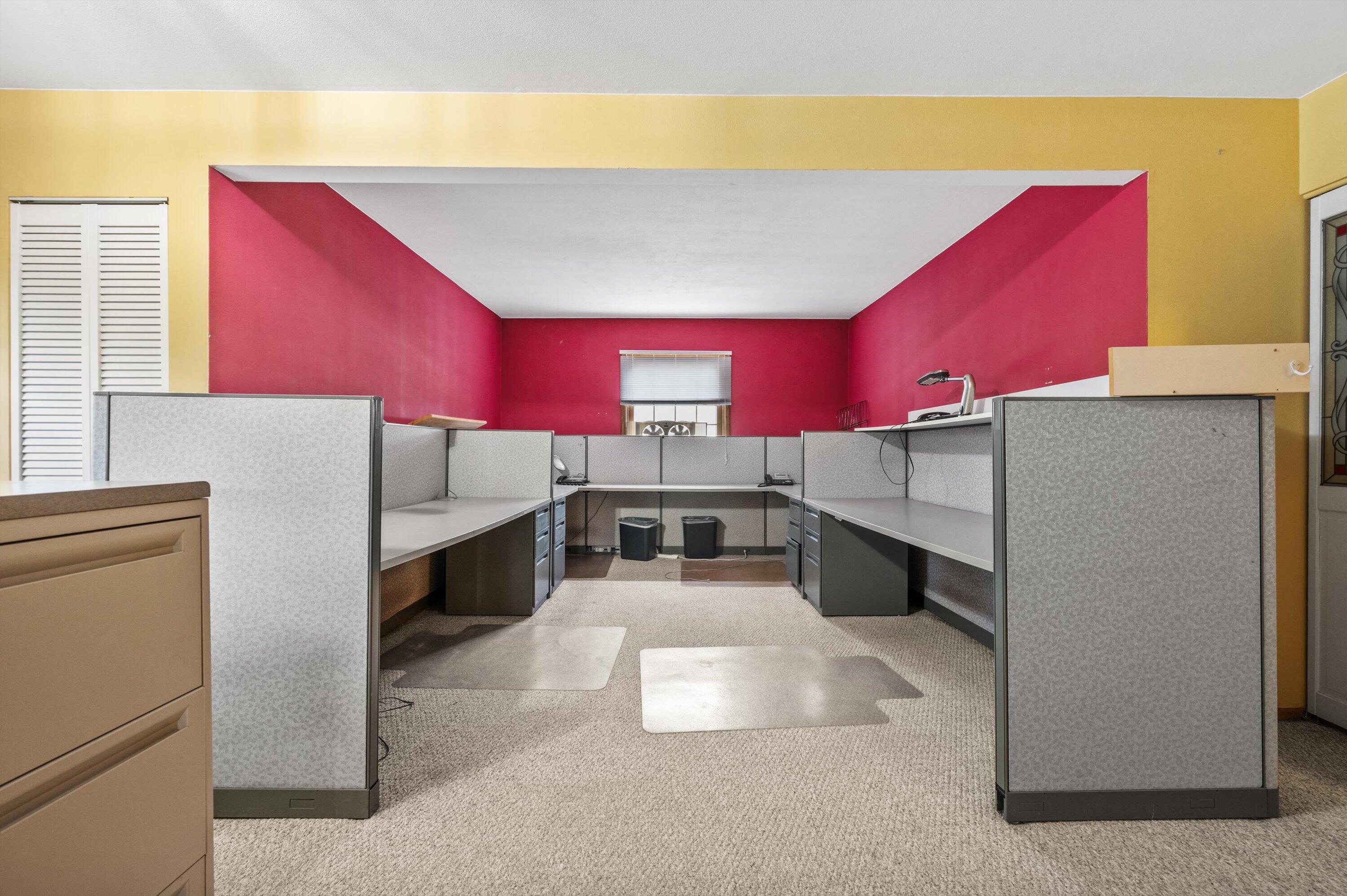 Office interior with gray cubicles and vivid pink and yellow walls.