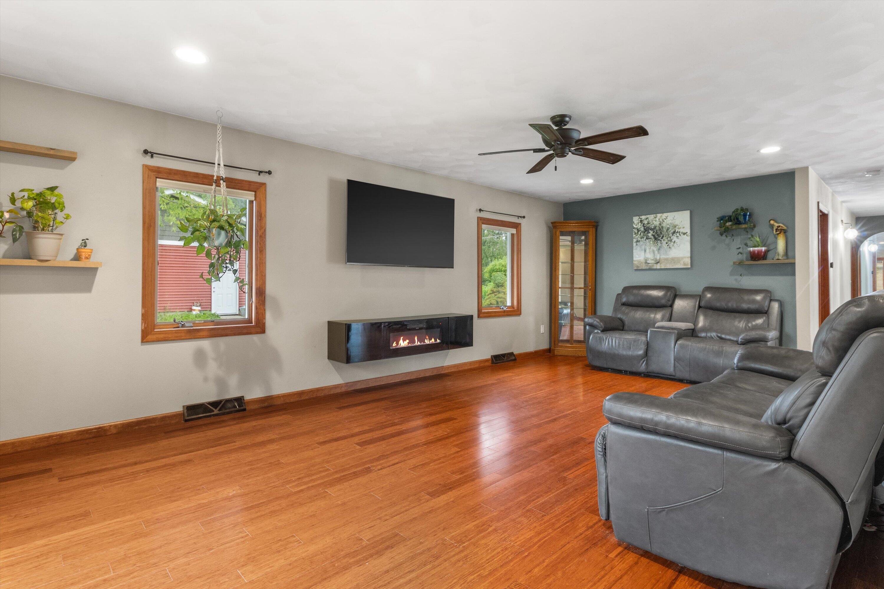 Living room with hardwood floors, leather recliners, and a wall-mounted fireplace